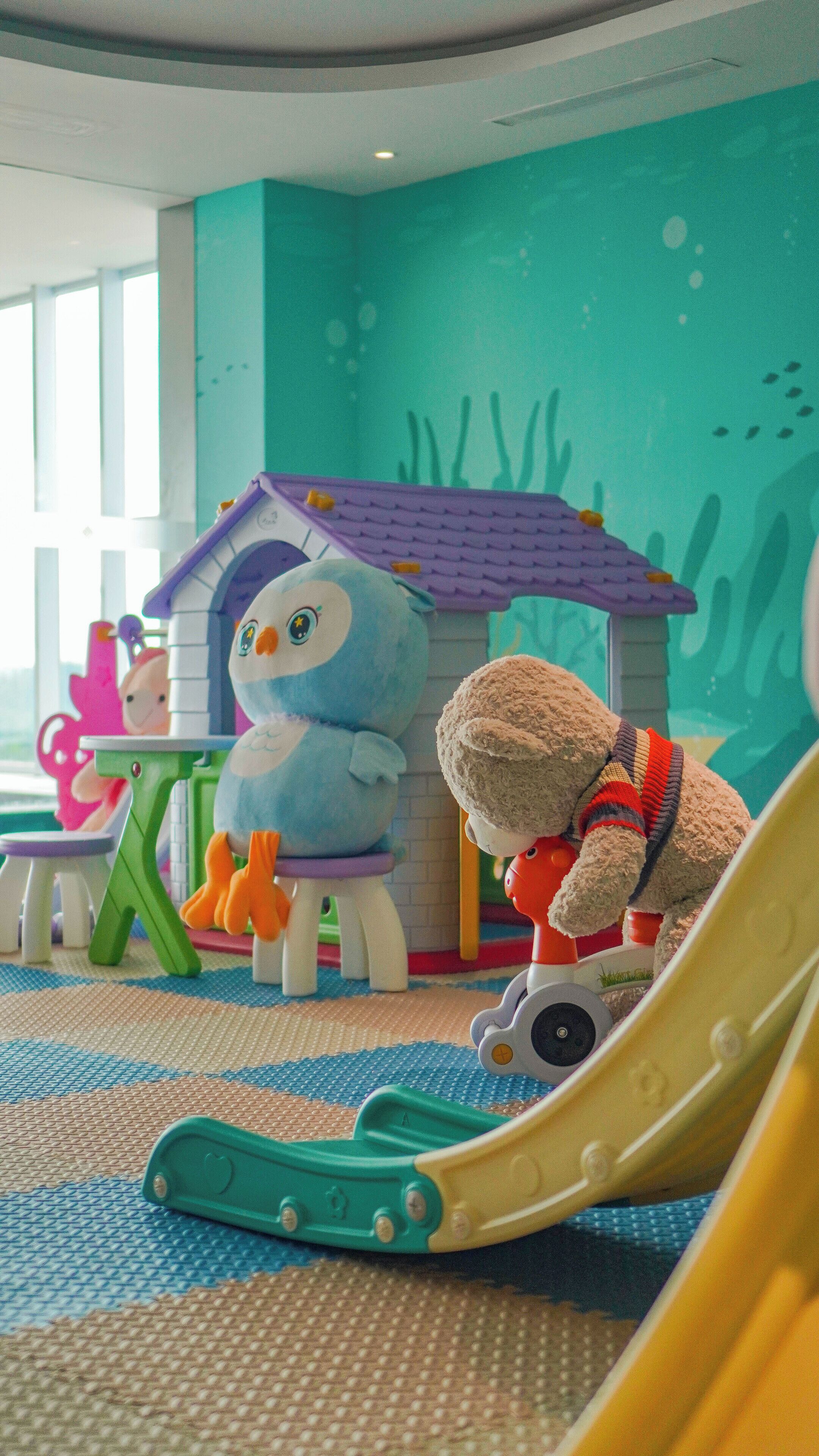 A children's play area with a slide, a toy house, and plush toys.