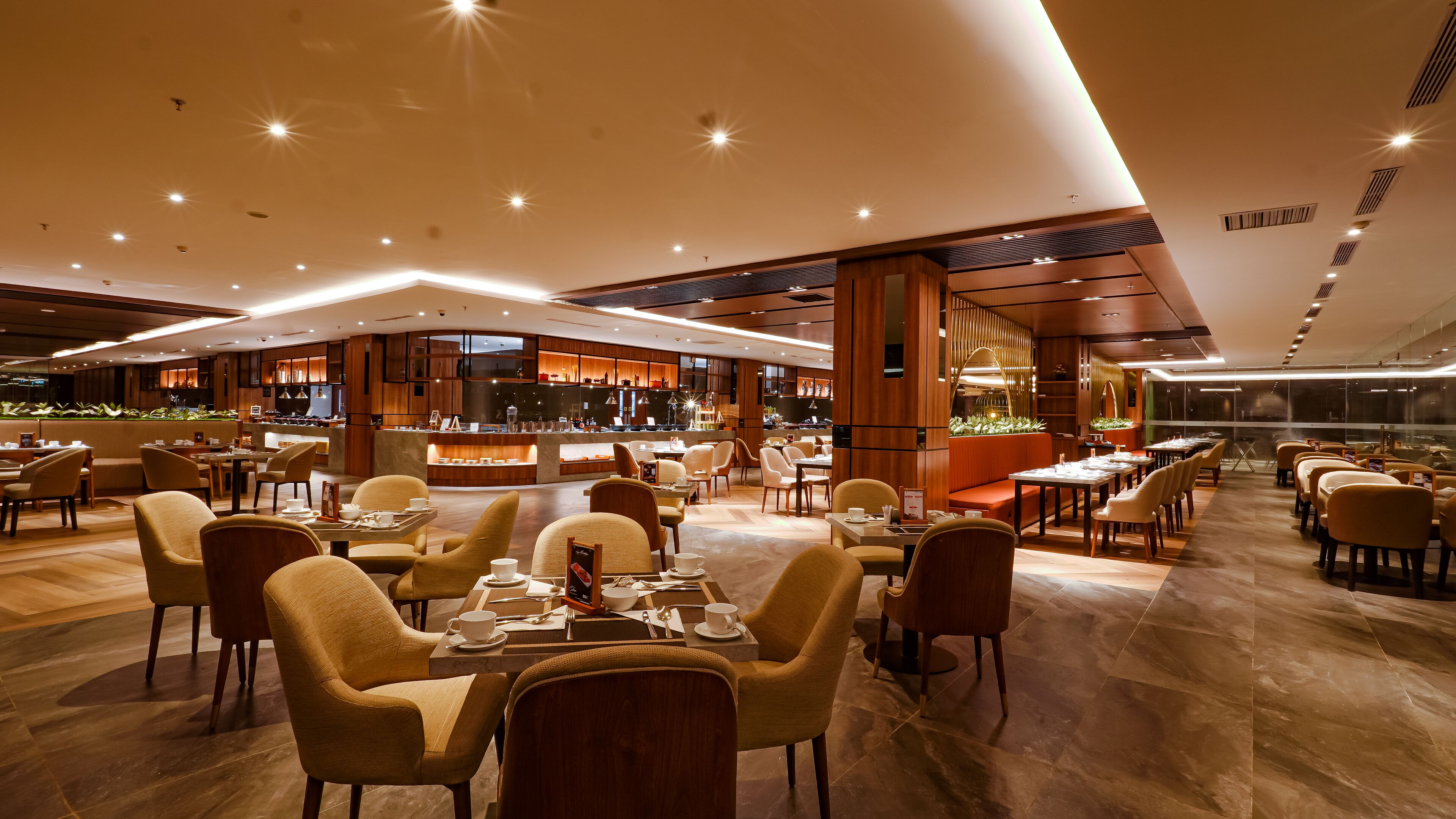 A modern restaurant with a bar area, multiple seating options, and a view of the cityscape through large windows.
