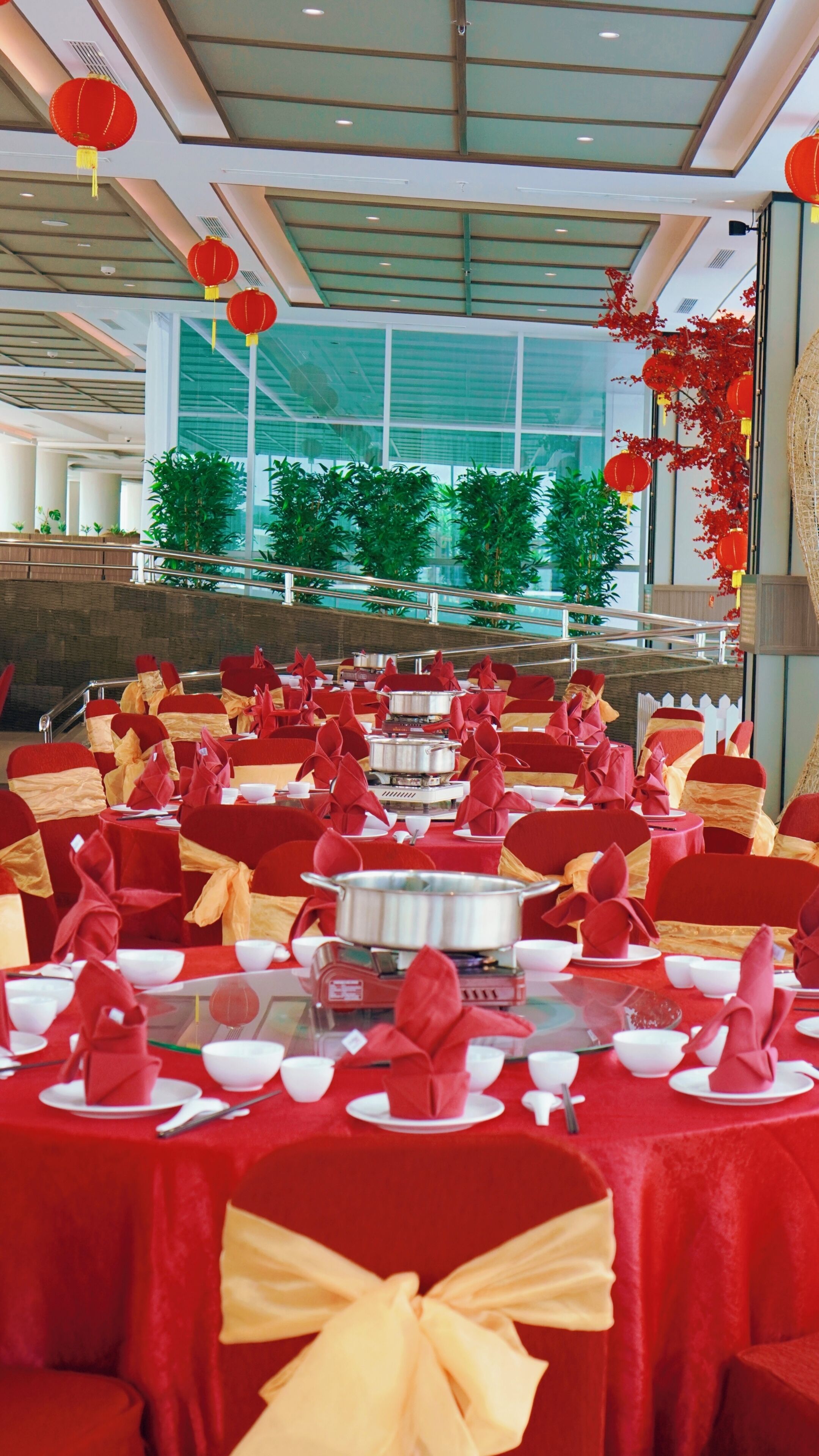 A banquet hall with tables set for a meal, featuring red chairs and yellow sashes.