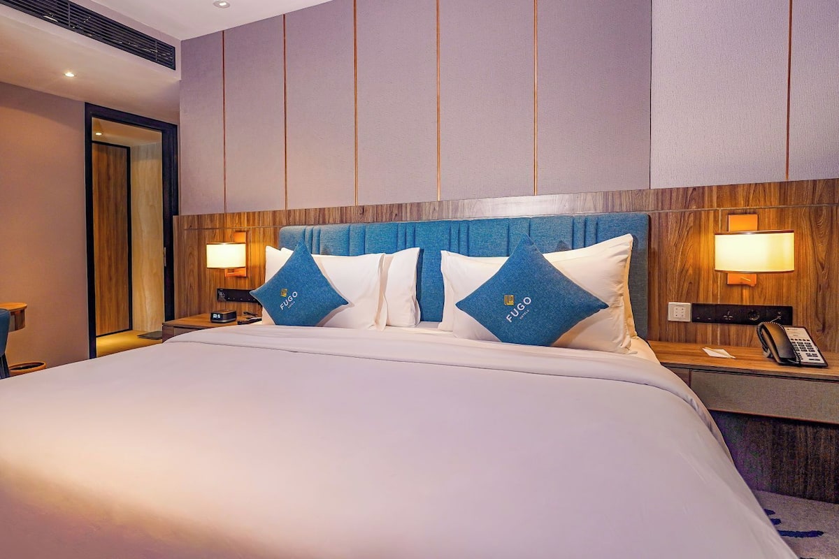 Ein Hotelzimmer mit einem großen Bett, zwei Nachttischen mit Lampen, einem Schreibtisch und einem Stuhl.