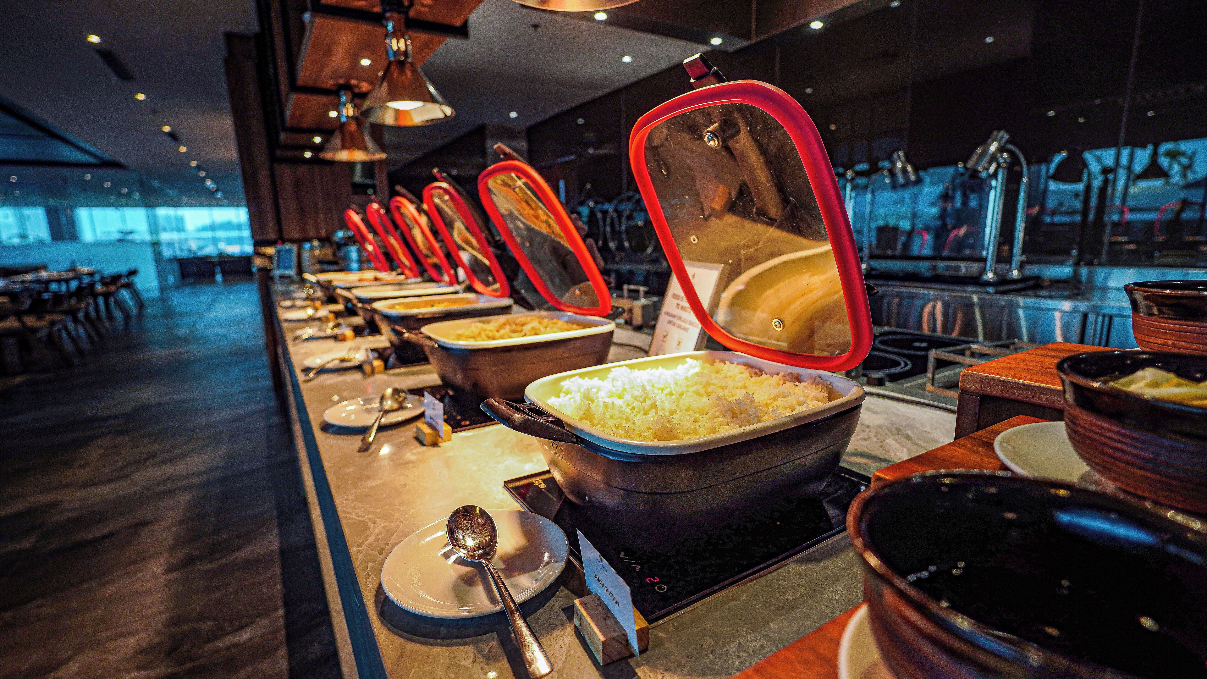 A buffet setup with various food containers and utensils.