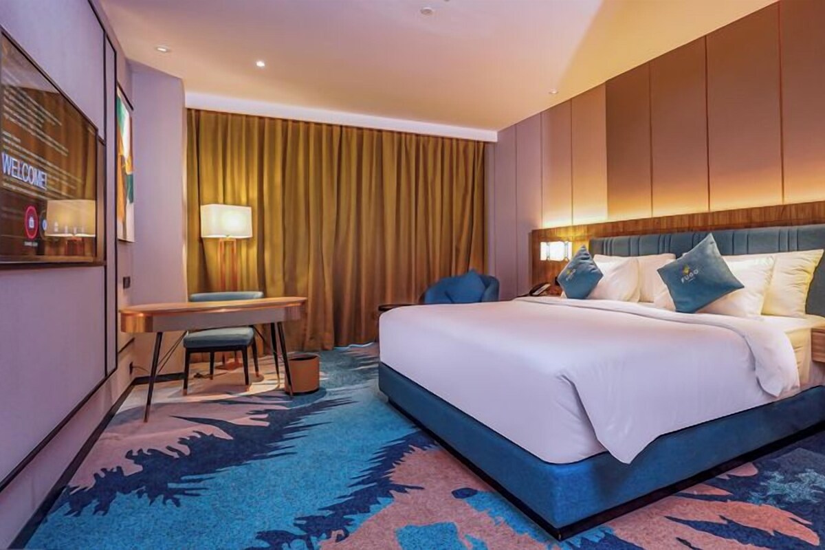 Una habitación de hotel con una cama grande, un escritorio, una silla y una mesita de noche.
