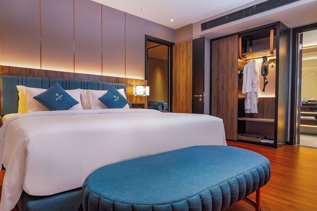 Ein Hotelzimmer mit einem großen Bett, Nachttischen, einem Schreibtisch und einem Kleiderschrank.