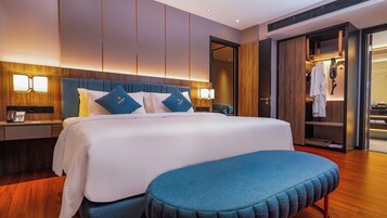 Una habitación de hotel con una cama grande, mesitas de noche, un escritorio y un armario.
