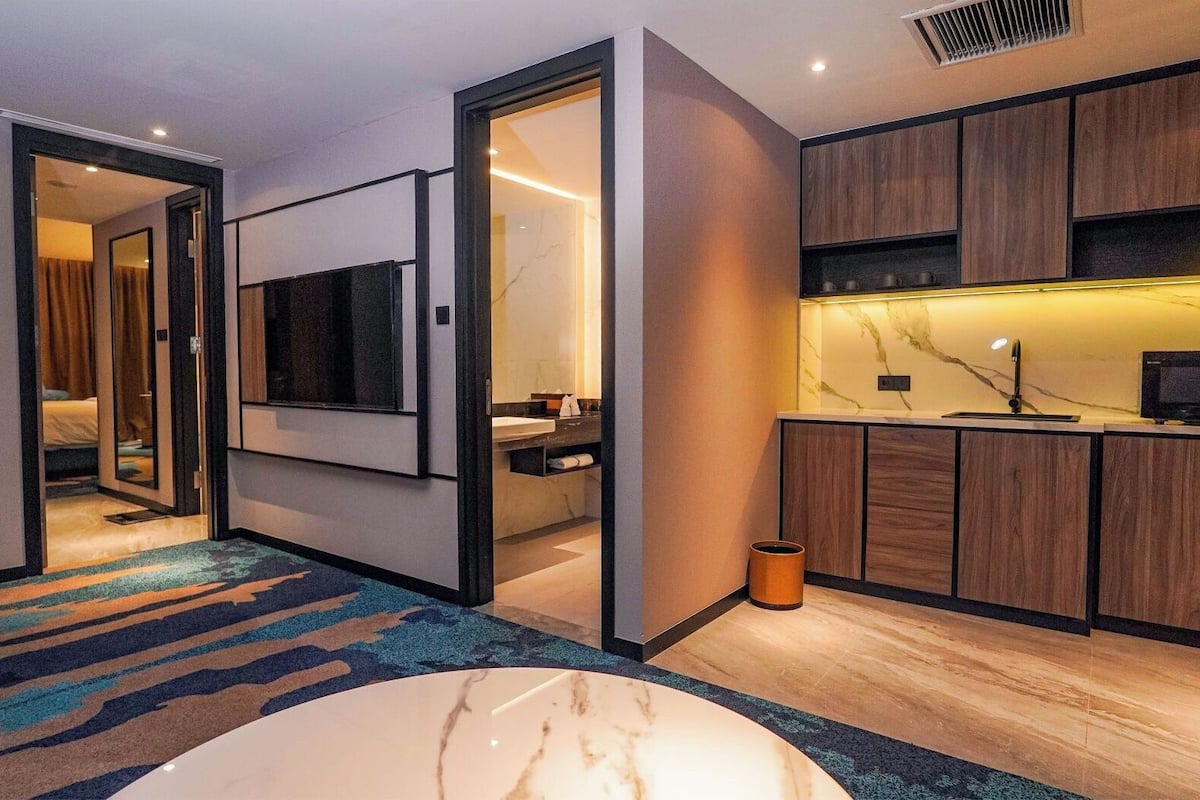 Ein modernes Hotelzimmer mit einem großen Bett, einem Fernseher, einem Badezimmer und einer Küchenzeile.