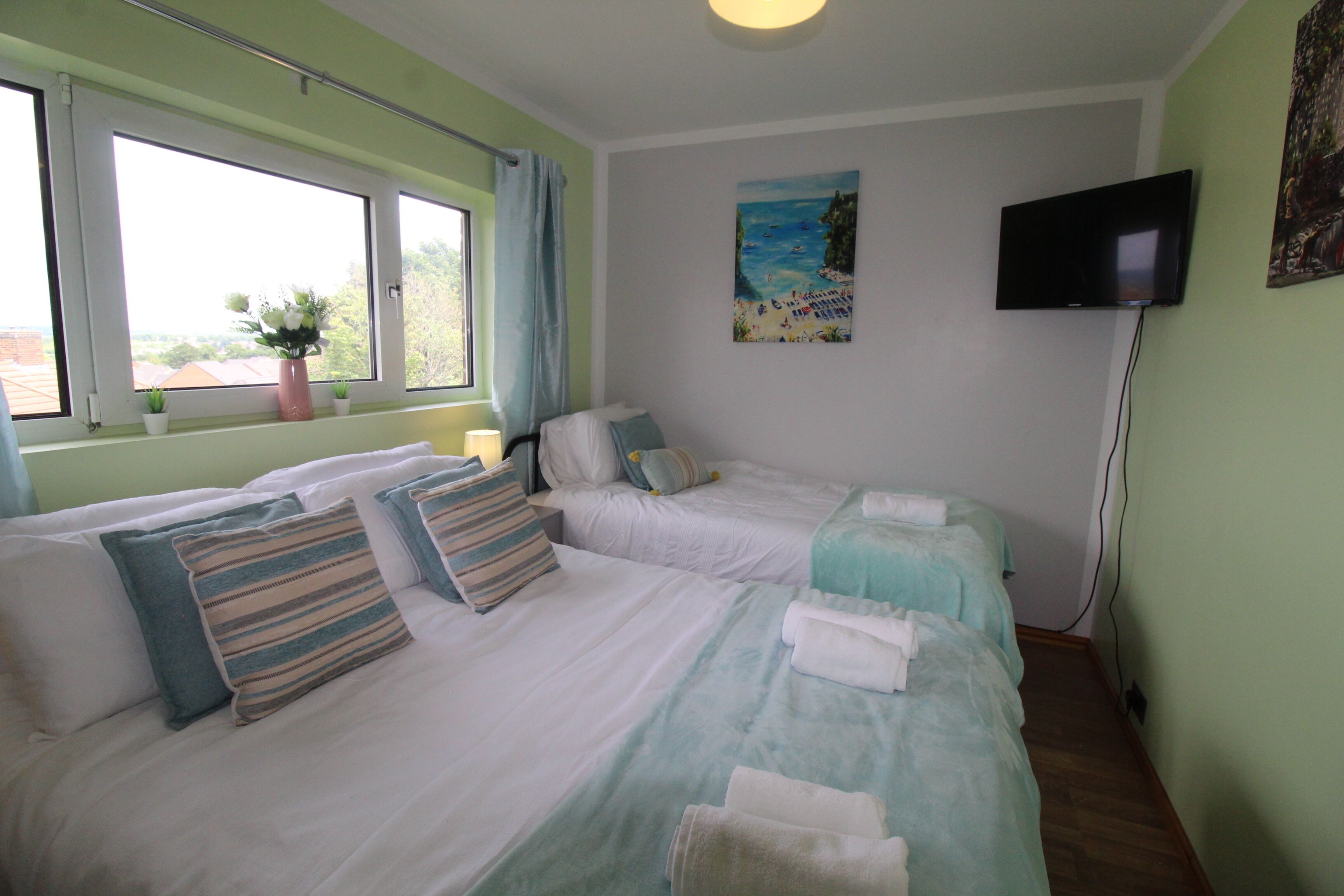 Quarto de hotel com duas camas, televisão e um quadro na parede.