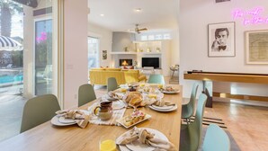 A dining area with a table set for breakfast, a fireplace, and a neon sign on the wall.