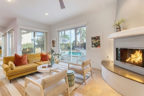 A modern living room with a sofa, chairs, a coffee table, and a fireplace.