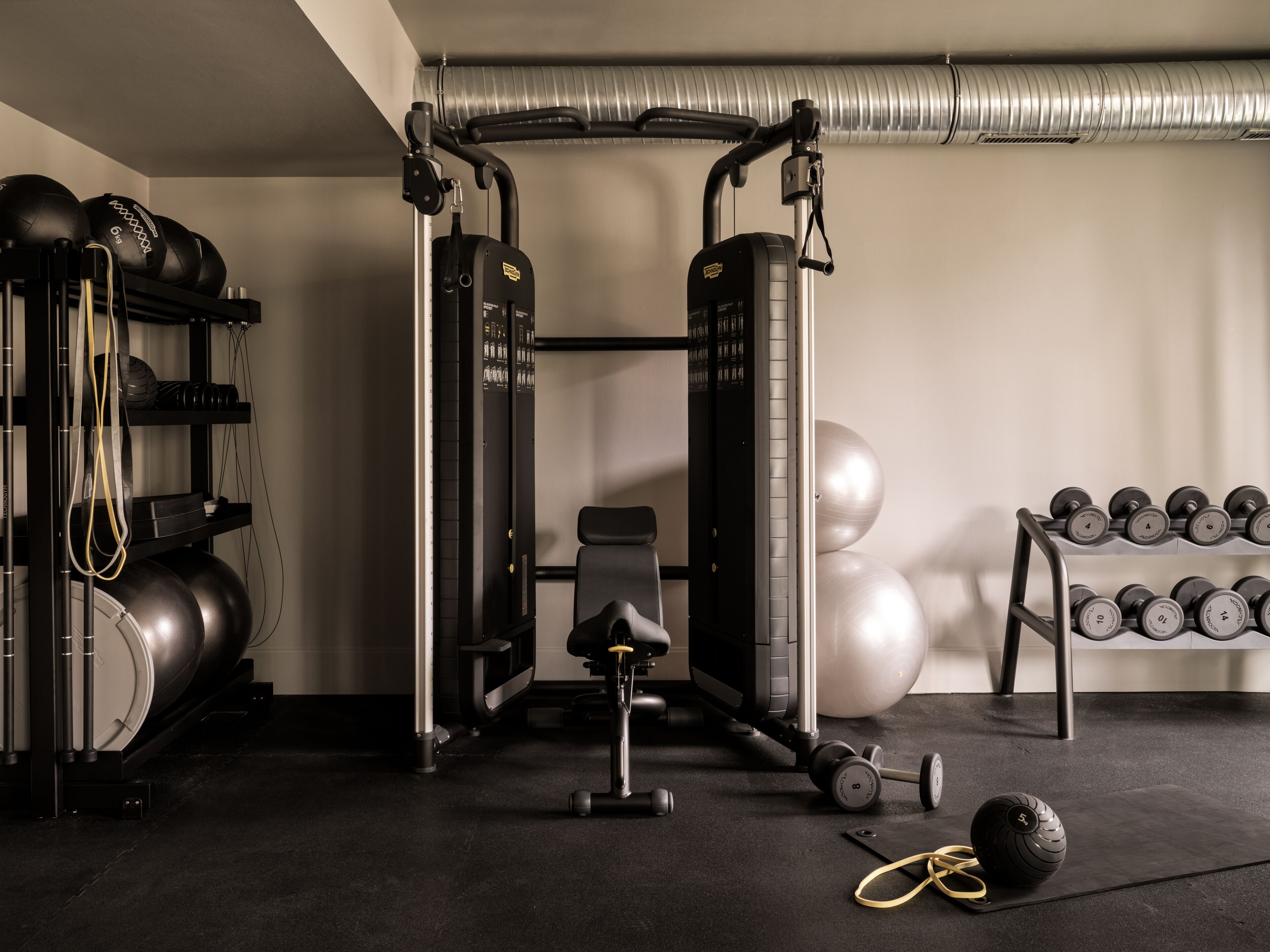 Ein Fitnessstudio mit Squat Rack, einer Bankpresche und verschiedenen Gewichten.