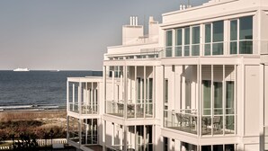 Un edificio moderno frente al mar, con varios balcones, ventanas amplias y vistas al océano.