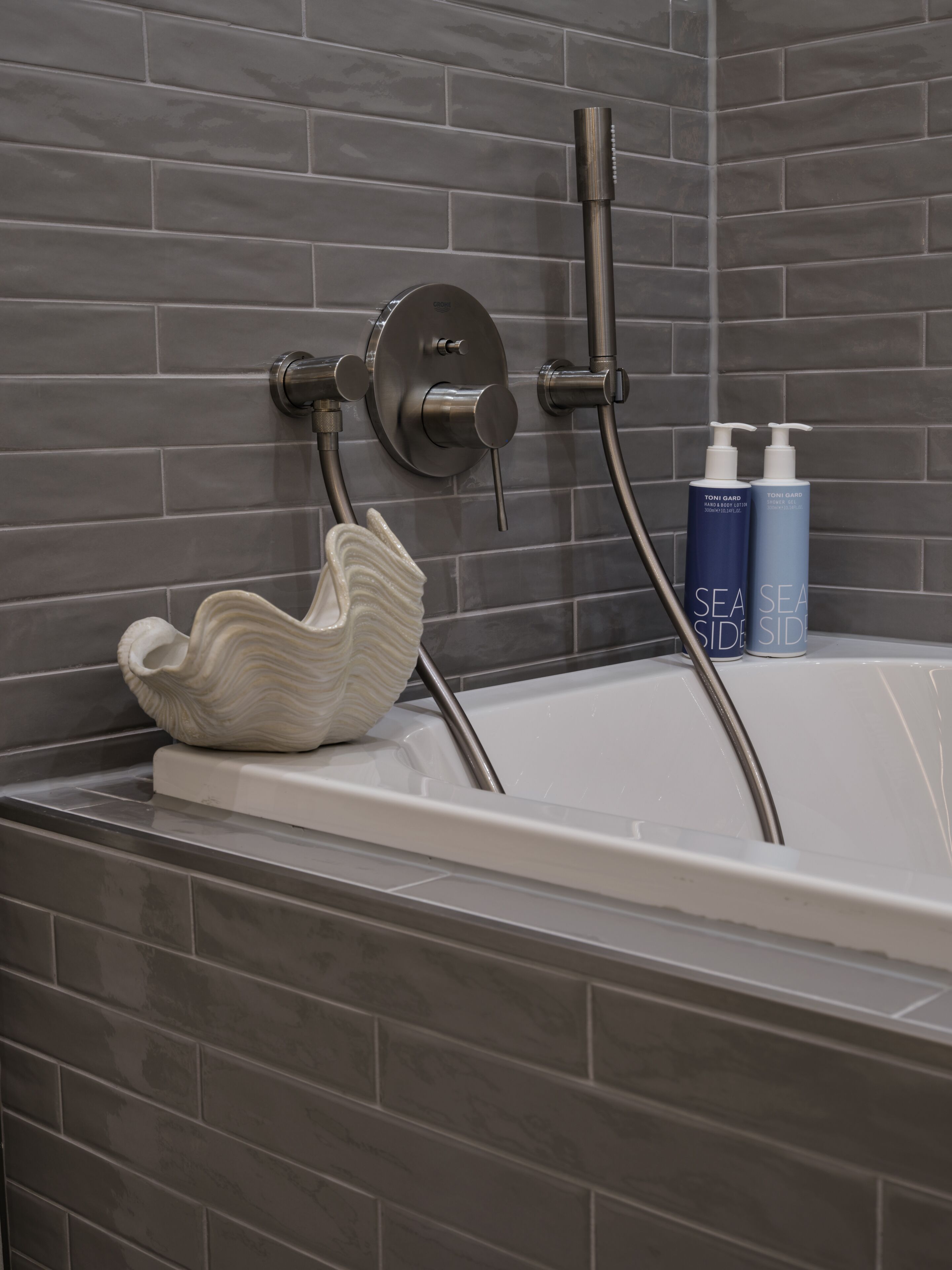 Une salle de bain équipée d’une baignoire, d’une douche et de deux flacons de produits de toilette.