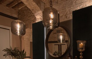 Una habitación con un espejo grande, dos lámparas colgantes, un candelabro y una planta en maceta.