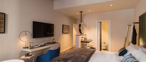 Una habitación de hotel moderna con una cama grande, un escritorio con una silla, un televisor y un baño.