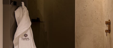 Une salle de bain moderne dotée d’une douche à parois de verre, d’un porte-serviettes avec une serviette blanche et d’un panneau de commande de douche bien visible.