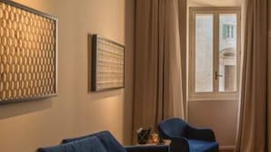 Une pièce avec un canapé bleu, un motif décoratif sur le mur et une fenêtre avec des rideaux.