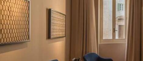 A room with a blue sofa, a patterned wall decoration, and a window with curtains.