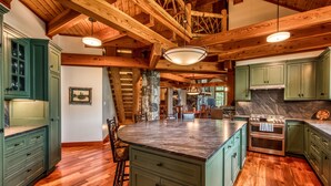 A spacious kitchen with wooden beams, green cabinets, and a large island. - Gorgeous lake views, walk to village, luxury chalet with 6,000+ sq (Lake Placid)