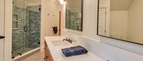 A modern bathroom with a glass shower enclosure, a large mirror, and a double sink vanity.