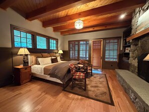 A bedroom with a bed, two bedside lamps, a chair, a fireplace, and large windows. - Gorgeous lake views, walk to village, luxury chalet with 6,000+ sq ft (Lake Placid)