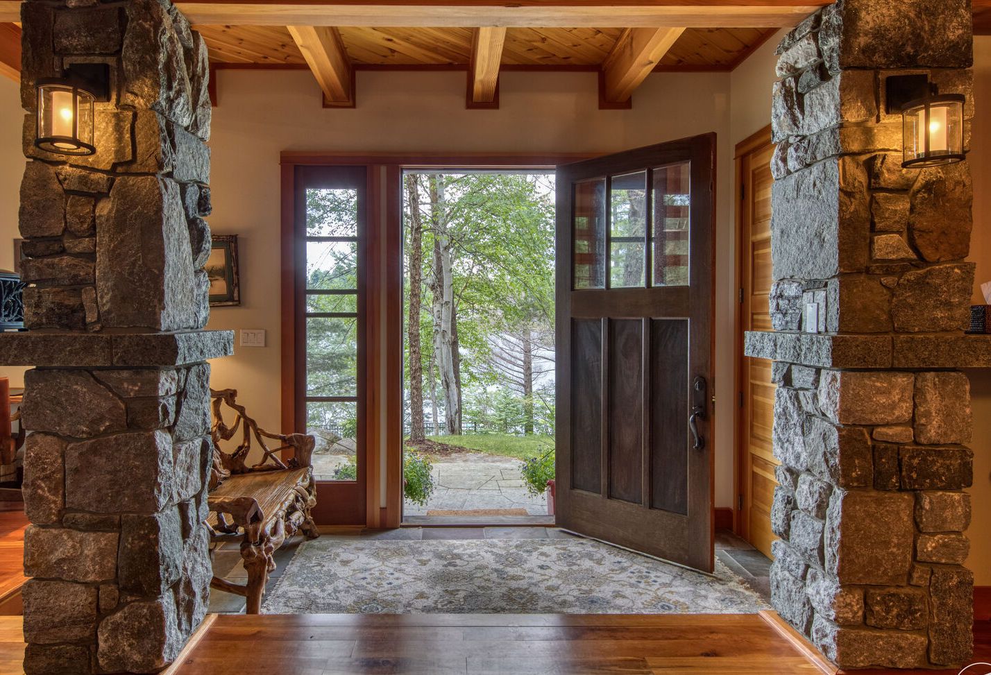 A stone-walled interior leading to a glass door with a view of trees outside.