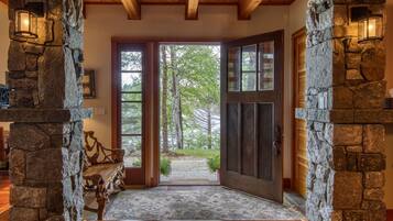 A stone-walled interior leading to a glass door with a view of trees outside.