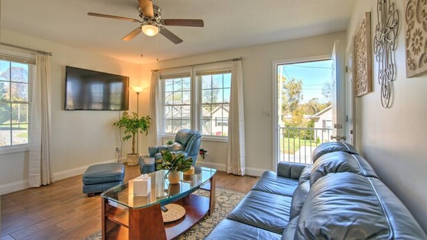 A spacious living room with a glass coffee table, leather sofa, and a ceiling fan. - Minutes to local attractions, interstates, and places of interest such as JCMC, ETSU, the the VA. (Johnson City)