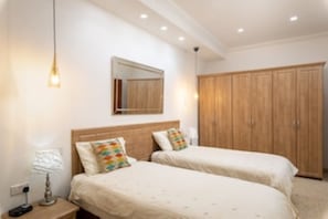 Ein Schlafzimmer mit zwei Betten, einem Holzschrank, einem Spiegel und einem Nachttisch mit Lampe.