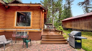 Une cabane en rondins dotée d’un patio, d’un barbecue et de meubles d’extérieur.