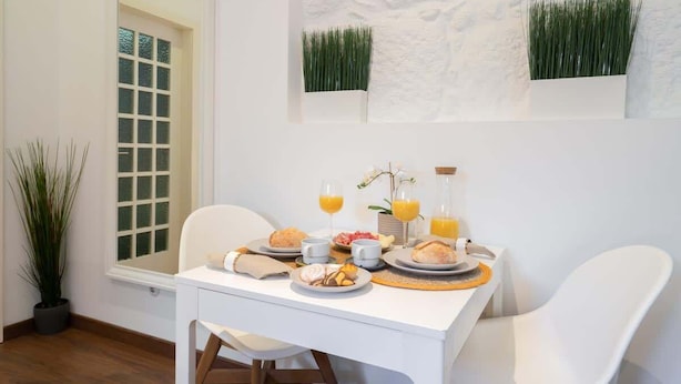 Uma mesa de café da manhã com pratos de comida, copos de suco de laranja e um vaso com flores.