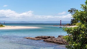 Een kustlandschap met helder water, een zandstrand en rotsformaties.