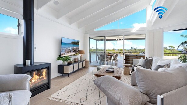 Een moderne woonkamer met een open haard, een televisie, een balkon met buitenmeubilair en een prachtig uitzicht.