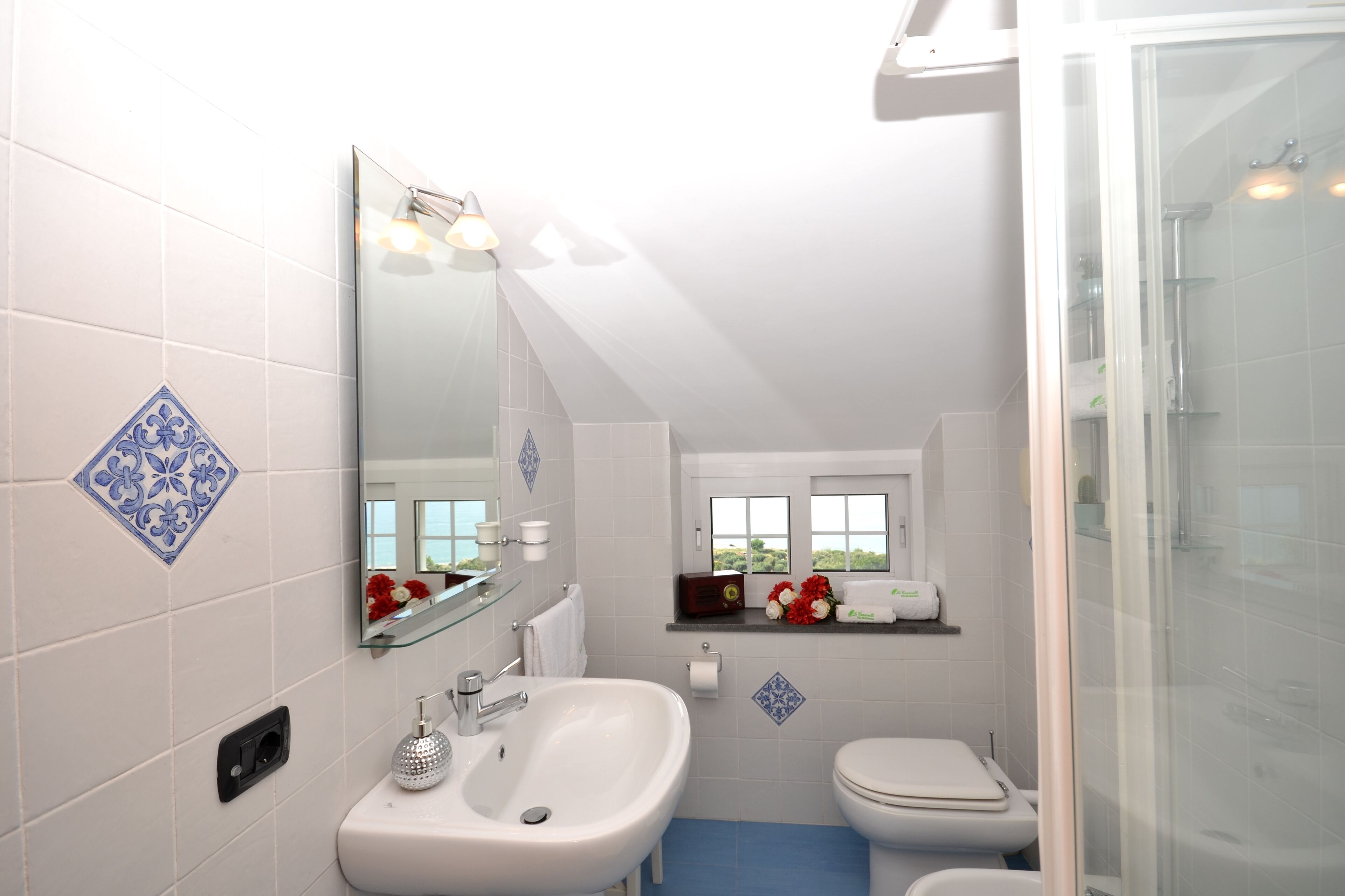A bathroom with a white sink, a mirror, a toilet, and a shower.