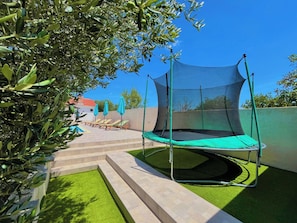 Relax and bounce into leisure time with a trampoline and lounge chairs in this outdoor recreational area.