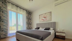 A bedroom with a large bed, a nightstand, a wall-mounted air conditioning unit, and a window with curtains. - Holiday Home Mary with Pool (Policnik)