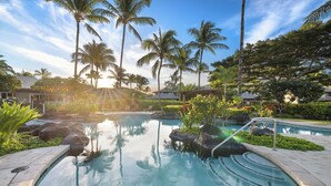 A pool area with palm trees, a clear sky, and a sunlit setting. - Gorgeous upgraded townhome + FREE Golf Cart! (Kamuela)