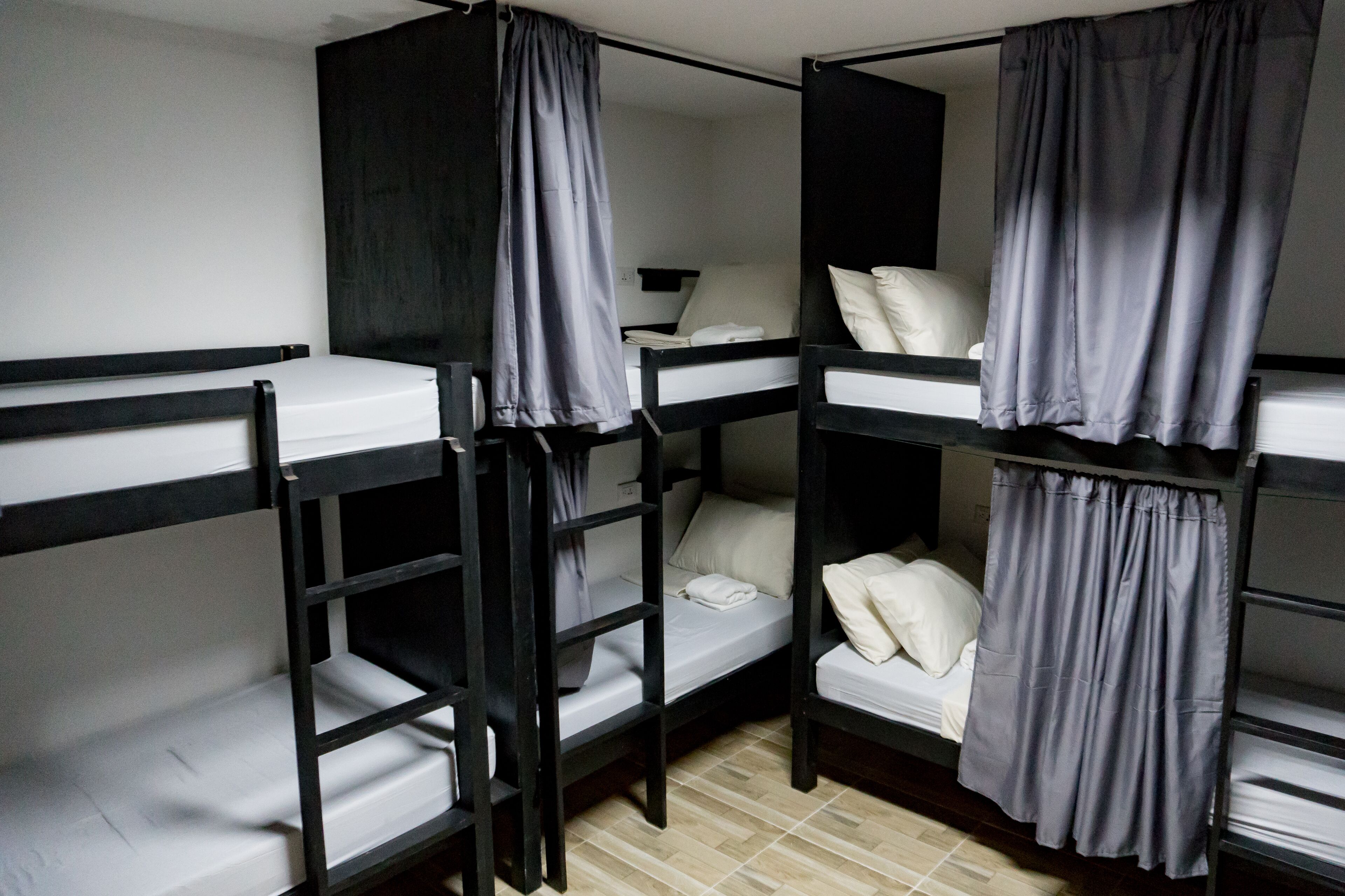 A dormitory-style room with bunk beds, each with a pillow and a blanket.
