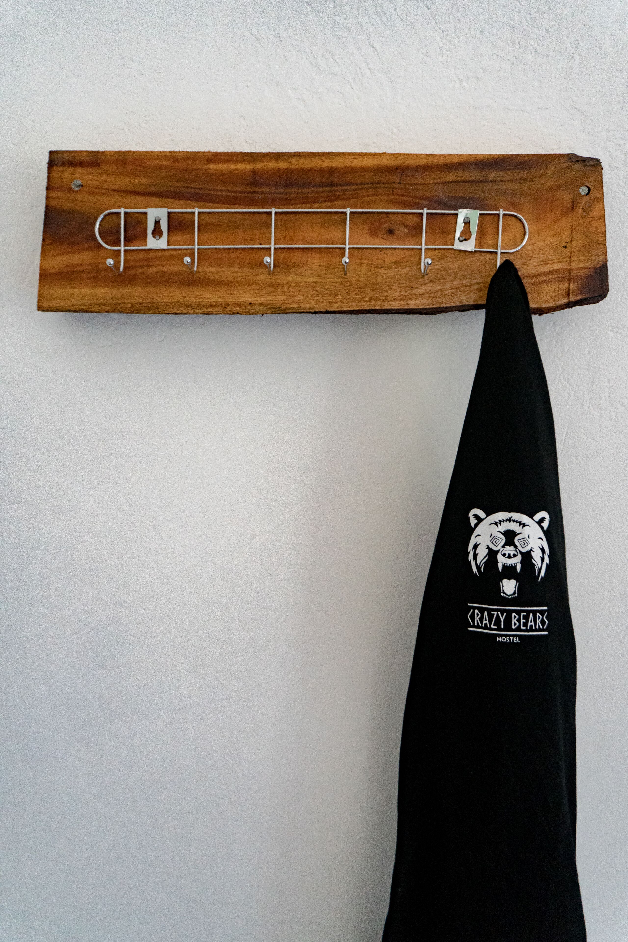 A wooden pegboard with hooks and a black cloth hanging from it.
