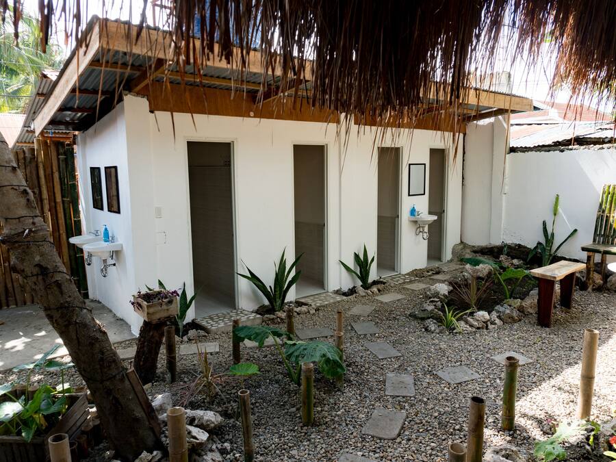A courtyard with a white building, a wooden bench, and a small table.