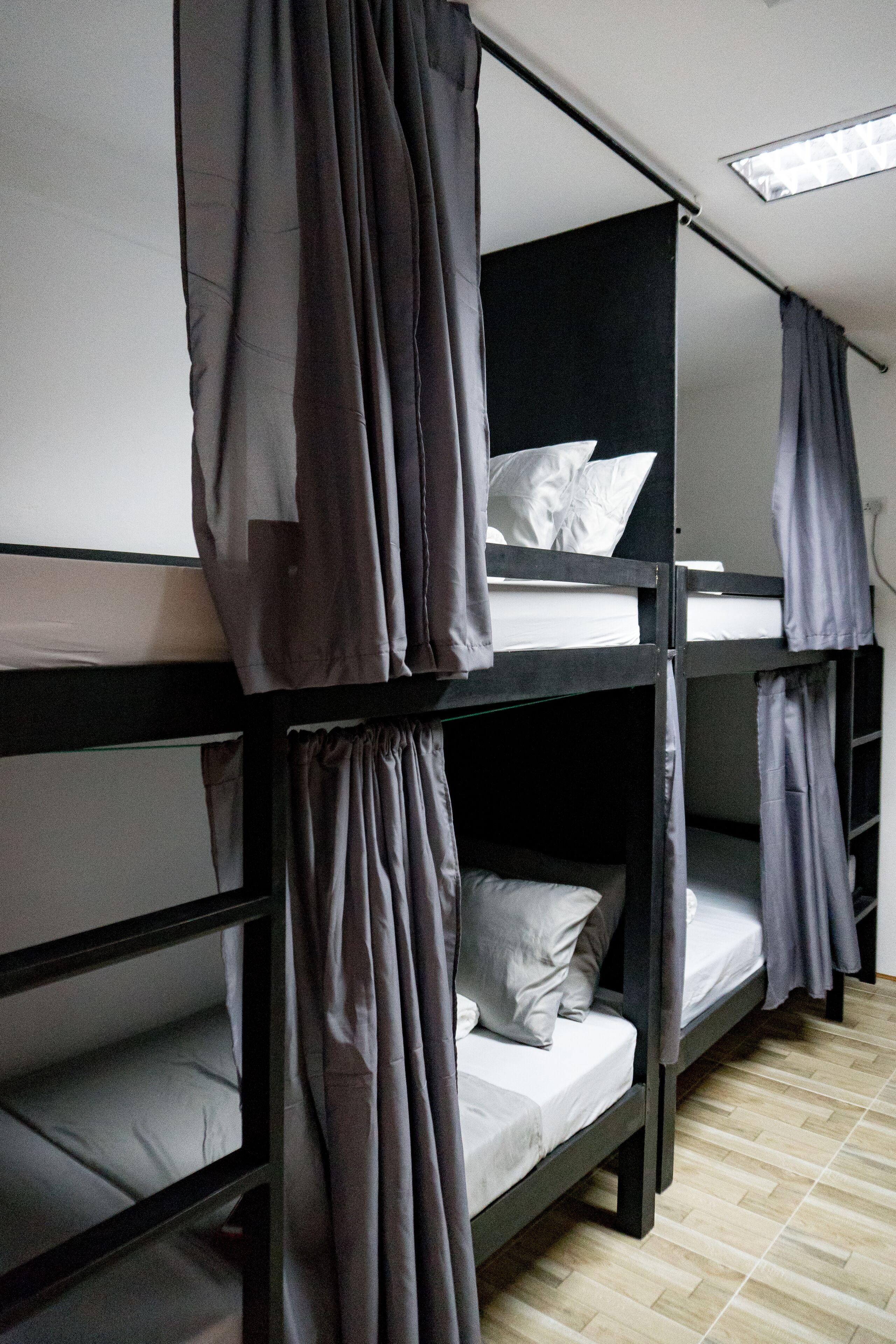 A bunk bed room with curtains, a skylight, and a wooden floor.