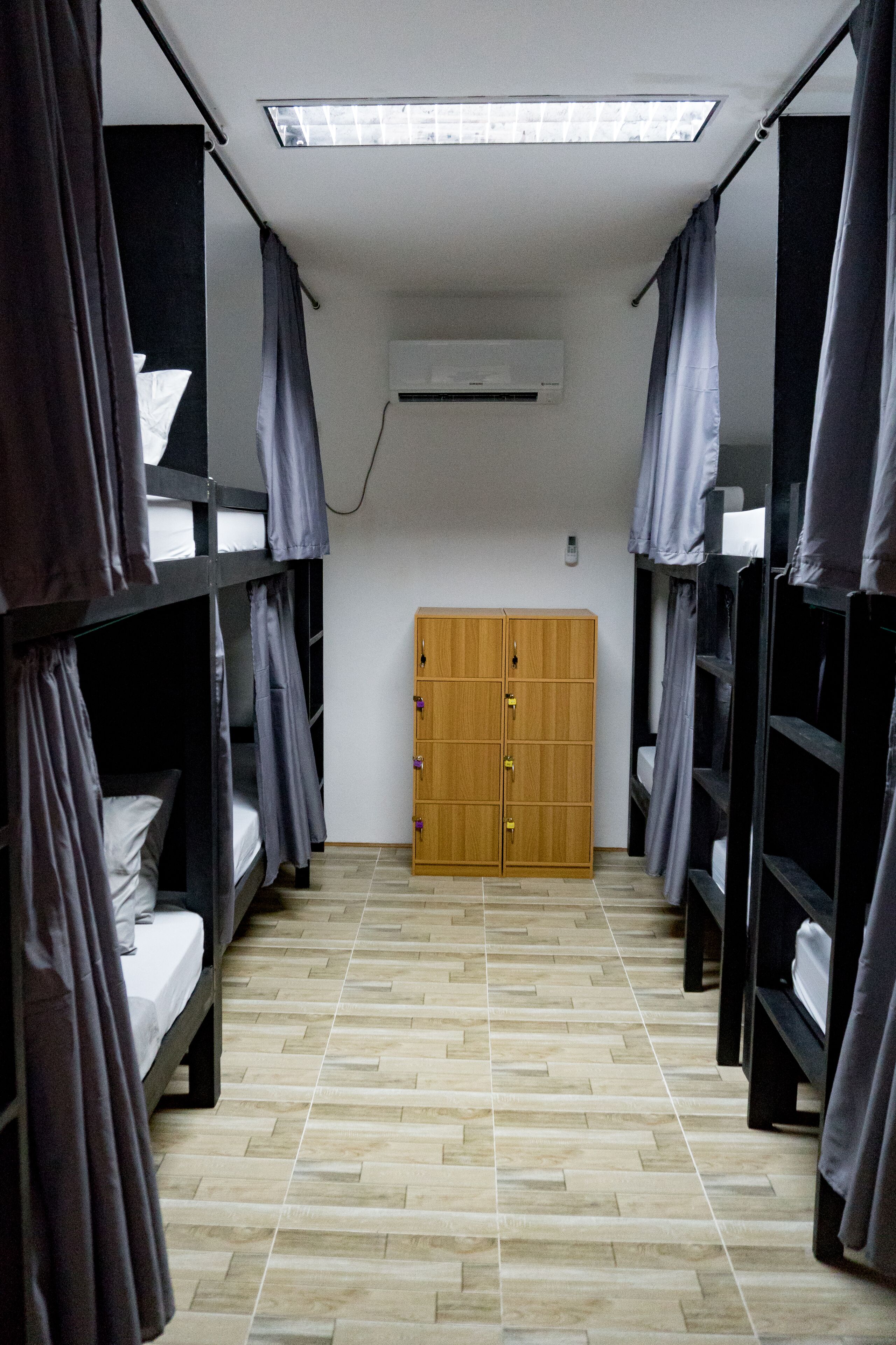 A dormitory room with bunk beds, a wooden wardrobe, and a skylight.