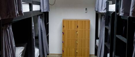 A dormitory room with bunk beds, a wooden wardrobe, and a skylight.