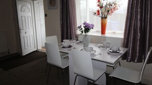 A dining area with a white table set for four, including plates, bowls, and cutlery. - Chadwick House (Sheffield)