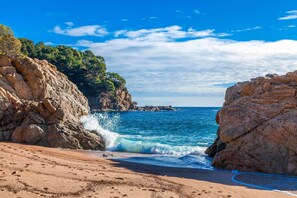 A beach with rocky cliffs and clear blue water.