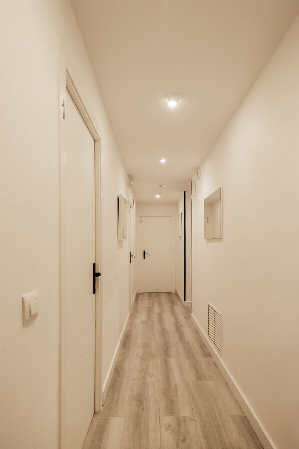Un couloir aux murs blancs, au plancher en bois et doté d’un éclairage encastré.