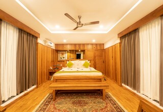 A bedroom with a wooden bed, a ceiling fan, and a patterned rug.
