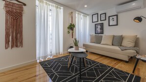 Un salon moderne avec un canapé, une table basse et une décoration en macramé suspendue.