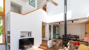 A spacious living area with a TV, seating, a fireplace, and a staircase leading to an upper level.