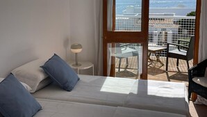 A bedroom with a bed, a nightstand, and a view of the balcony.