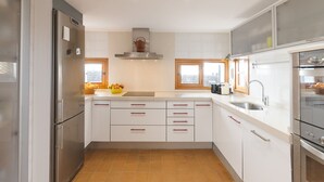 A modern kitchen with white cabinets, stainless steel appliances, and a tiled floor.