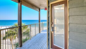 A wooden deck with a glass door leading to a beach view. - Sandpiper 16C ~ deluxe beach front condo ~ sleeps 6 (Gulf Shores)